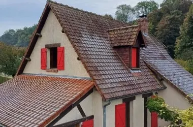 Avant : toiture en tuiles d’une maison normande à colombages, couverte de mousses